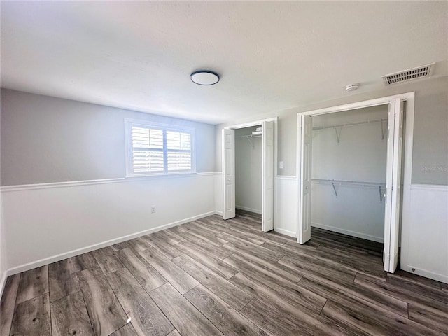 unfurnished bedroom featuring dark hardwood / wood-style flooring and two closets