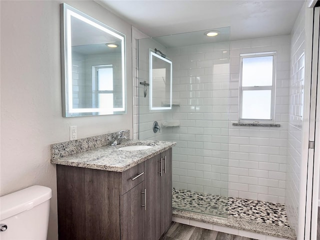 bathroom with vanity, wood-type flooring, toilet, and a tile shower