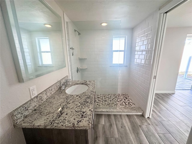 bathroom featuring a tile shower, vanity, and hardwood / wood-style flooring