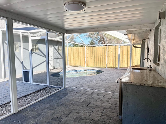 view of patio featuring sink, a swimming pool, and glass enclosure