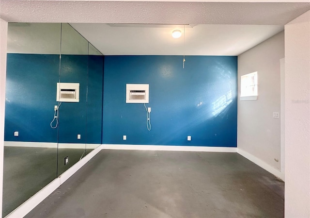 unfurnished room with a wall unit AC, concrete floors, and a textured ceiling