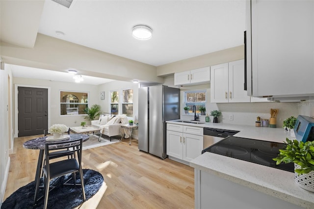 kitchen featuring sink, stainless steel appliances, light stone counters, white cabinets, and light wood-type flooring