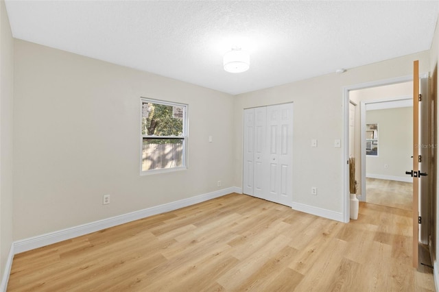 unfurnished bedroom with a textured ceiling, light hardwood / wood-style floors, and a closet