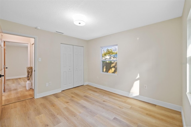 unfurnished bedroom with light hardwood / wood-style floors and a closet