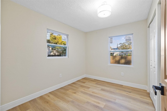 empty room with a textured ceiling and light hardwood / wood-style floors