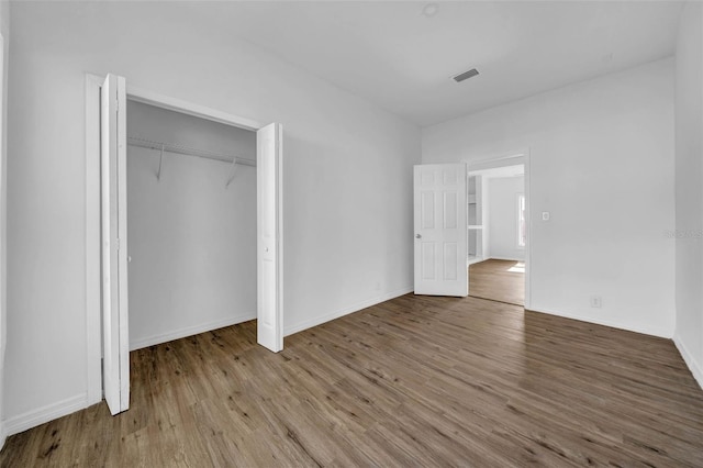 unfurnished bedroom with wood-type flooring and a closet