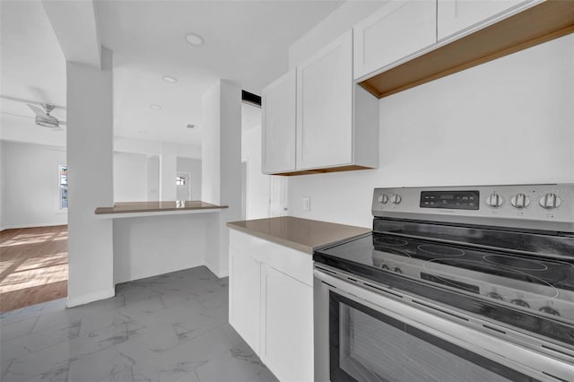 kitchen featuring stainless steel electric stove, white cabinetry, and ceiling fan