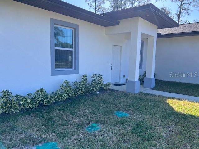 property entrance with a lawn