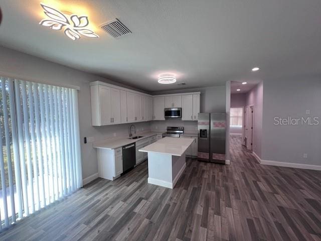 kitchen featuring a center island, sink, white cabinetry, stainless steel appliances, and dark hardwood / wood-style flooring