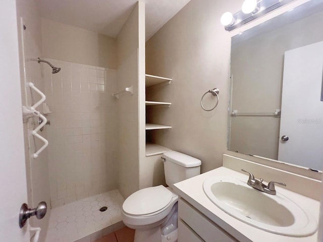 bathroom with tiled shower, tile patterned floors, vanity, and toilet