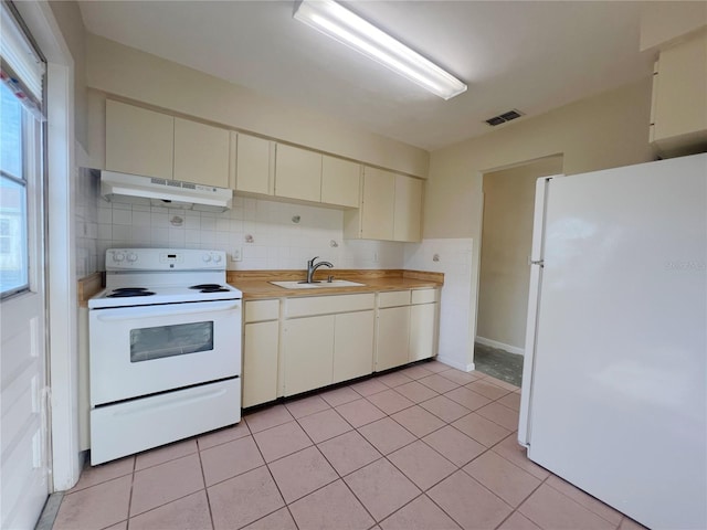 kitchen featuring white appliances, cream cabinetry, light tile patterned flooring, sink, and backsplash