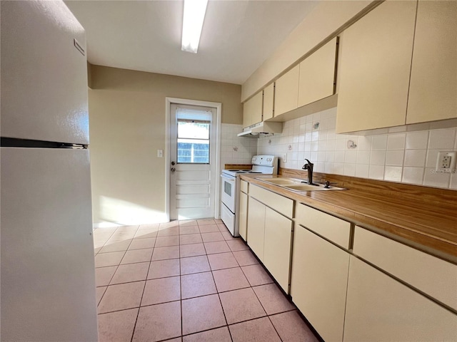 kitchen with sink, fridge, light tile patterned flooring, backsplash, and electric stove