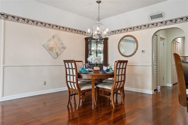 dining area with dark hardwood / wood-style floors and an inviting chandelier