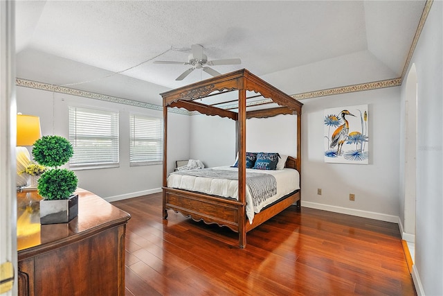 bedroom with a textured ceiling, ceiling fan, dark wood-type flooring, and vaulted ceiling