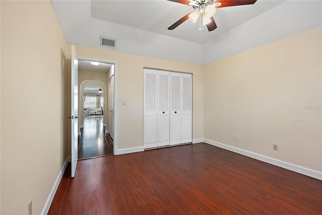 unfurnished bedroom featuring ceiling fan, dark hardwood / wood-style flooring, a raised ceiling, and a closet