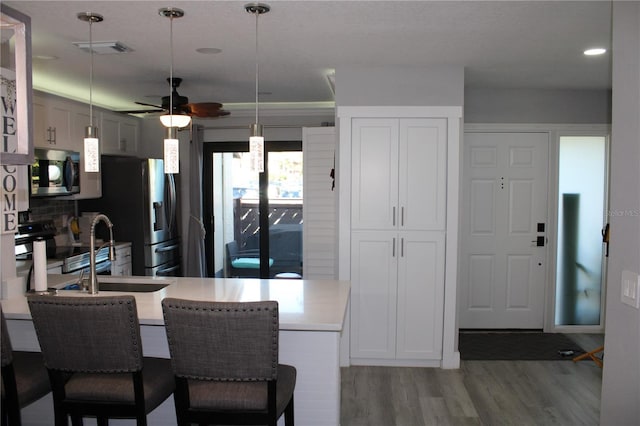 kitchen with a breakfast bar area, a peninsula, visible vents, appliances with stainless steel finishes, and light wood finished floors