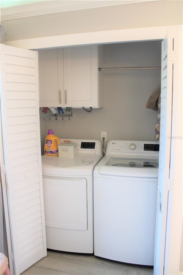 washroom featuring cabinet space, light wood-style flooring, and washer and dryer