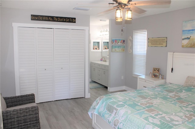 bedroom with connected bathroom, a sink, a ceiling fan, light wood-style floors, and a closet