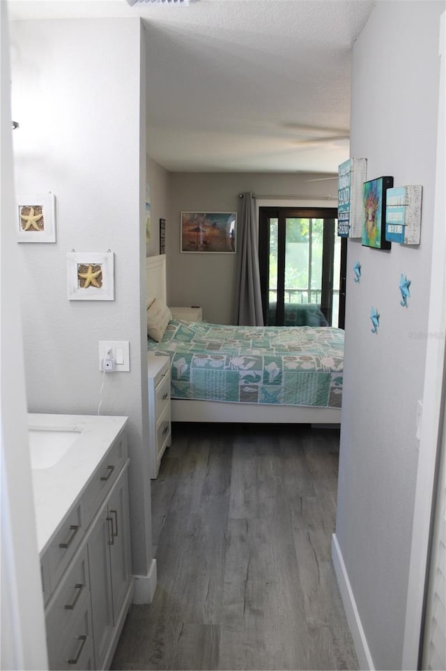 bedroom with a sink, access to outside, baseboards, and wood finished floors