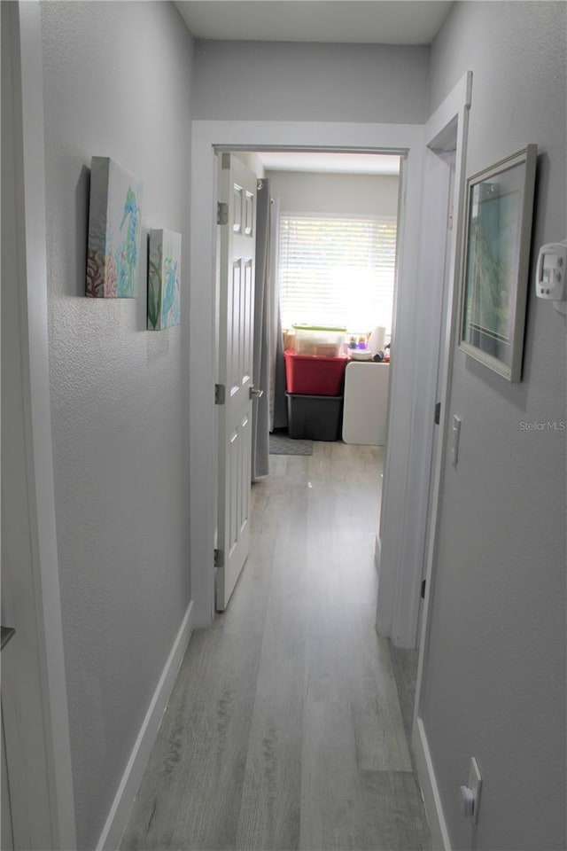 corridor with wood finished floors and baseboards