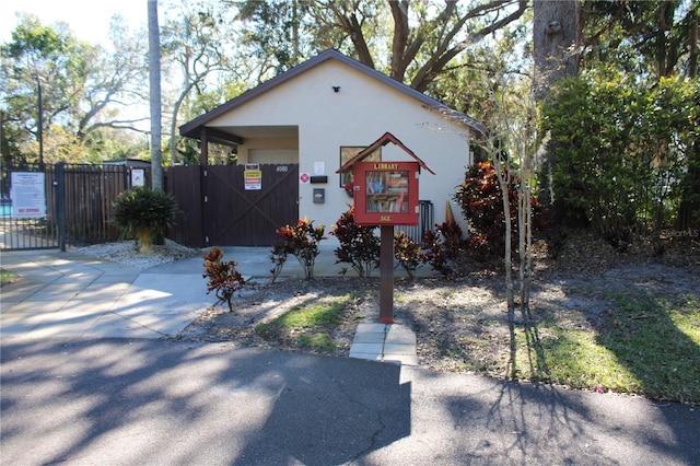 view of front of property with fence, a gate, and stucco siding