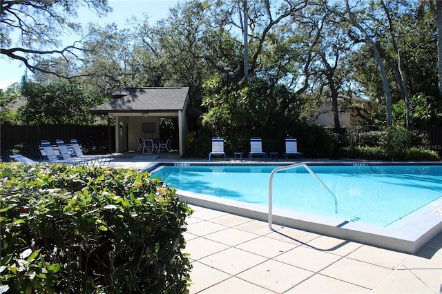 pool with an outbuilding, a patio area, and fence