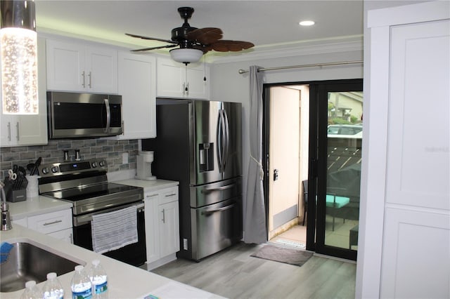 kitchen featuring stainless steel appliances, tasteful backsplash, light countertops, ornamental molding, and white cabinets