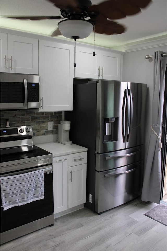 kitchen featuring light wood finished floors, tasteful backsplash, light countertops, appliances with stainless steel finishes, and white cabinetry