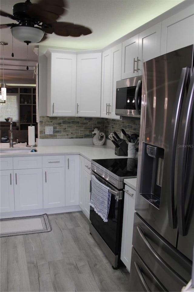 kitchen featuring a sink, white cabinets, light countertops, appliances with stainless steel finishes, and decorative backsplash