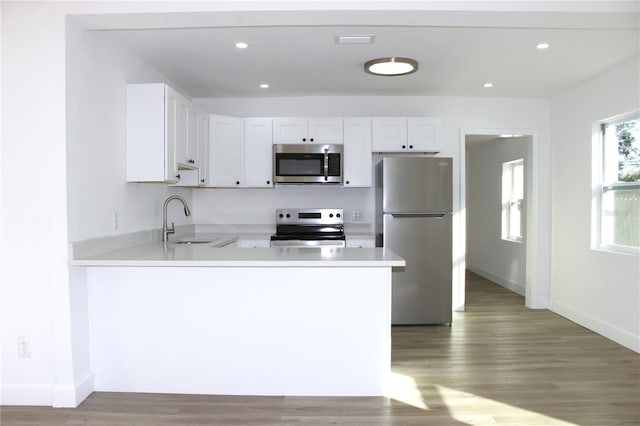 kitchen featuring kitchen peninsula, appliances with stainless steel finishes, white cabinetry, and sink