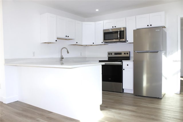 kitchen with kitchen peninsula, white cabinetry, and stainless steel appliances