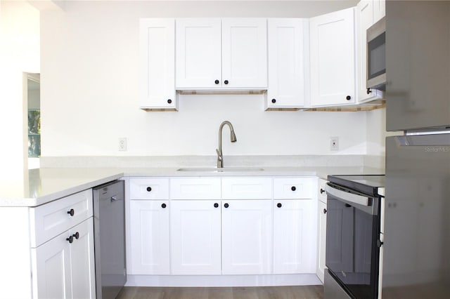 kitchen featuring sink, white cabinets, light hardwood / wood-style floors, and appliances with stainless steel finishes