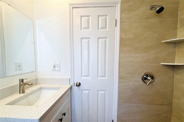 bathroom with a tile shower and vanity