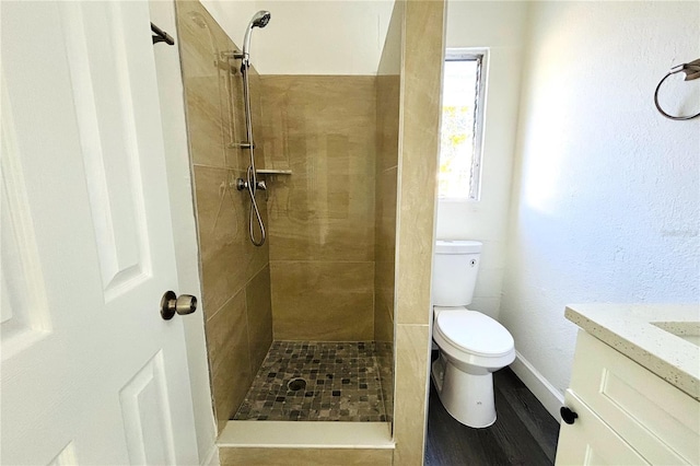 bathroom with a tile shower, vanity, and toilet