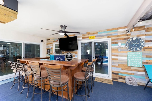 bar featuring wooden walls and ceiling fan