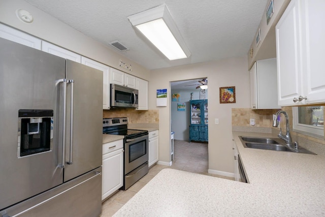 kitchen with white cabinets, appliances with stainless steel finishes, decorative backsplash, and sink