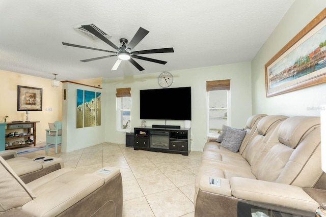 living room with ceiling fan, light tile patterned floors, and a textured ceiling