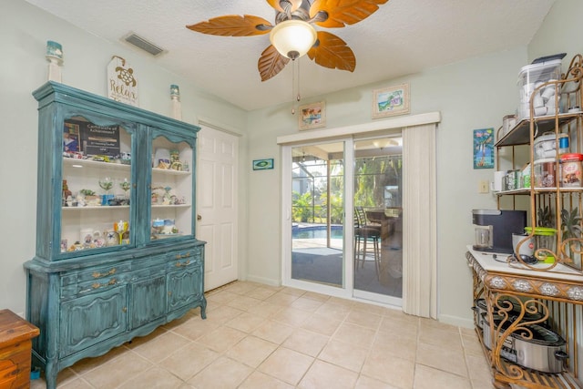 doorway to outside with ceiling fan, light tile patterned floors, and a textured ceiling