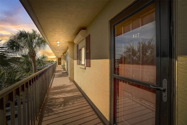 balcony at dusk featuring a wall mounted air conditioner