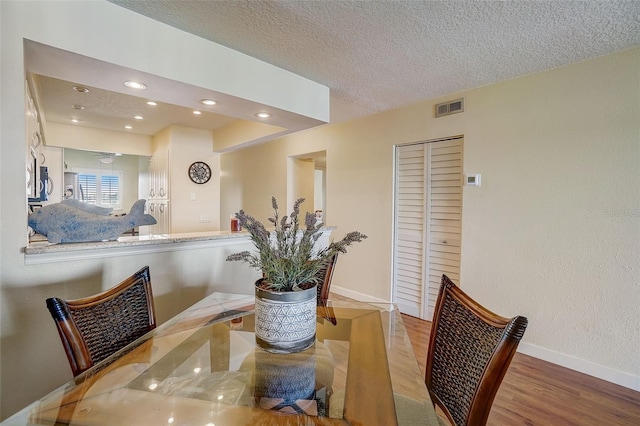 dining room with wood-type flooring and a textured ceiling