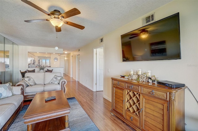 living room with ceiling fan, hardwood / wood-style floors, and a textured ceiling