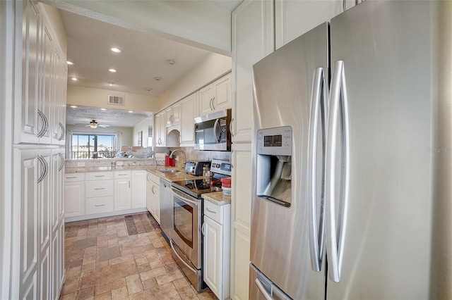 kitchen with sink, stainless steel appliances, kitchen peninsula, and white cabinets