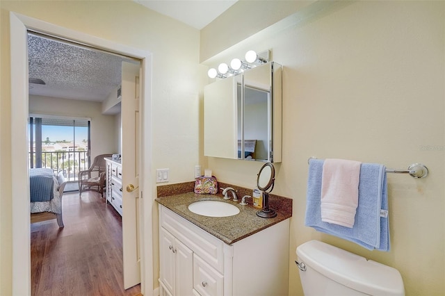 bathroom featuring hardwood / wood-style flooring, vanity, toilet, and a textured ceiling