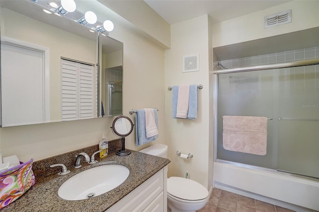 full bathroom featuring vanity, tile patterned floors, shower / bath combination with glass door, and toilet