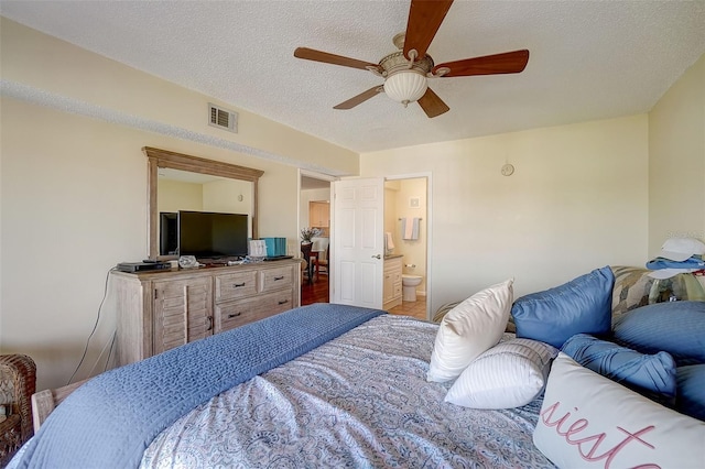 bedroom with ceiling fan, a textured ceiling, and ensuite bath