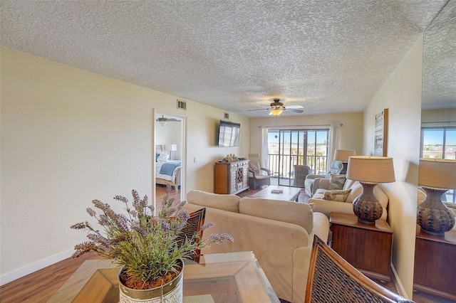 living room featuring hardwood / wood-style flooring, ceiling fan, and a textured ceiling