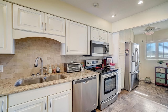 kitchen with sink, light stone counters, appliances with stainless steel finishes, white cabinets, and backsplash