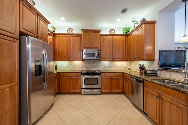 kitchen featuring hanging light fixtures, backsplash, dark stone counters, light tile patterned floors, and appliances with stainless steel finishes