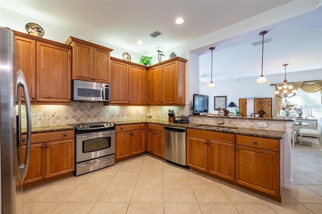 kitchen featuring sink, hanging light fixtures, kitchen peninsula, dark stone countertops, and appliances with stainless steel finishes