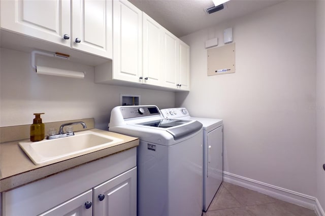 clothes washing area with light tile patterned flooring, cabinets, separate washer and dryer, and sink